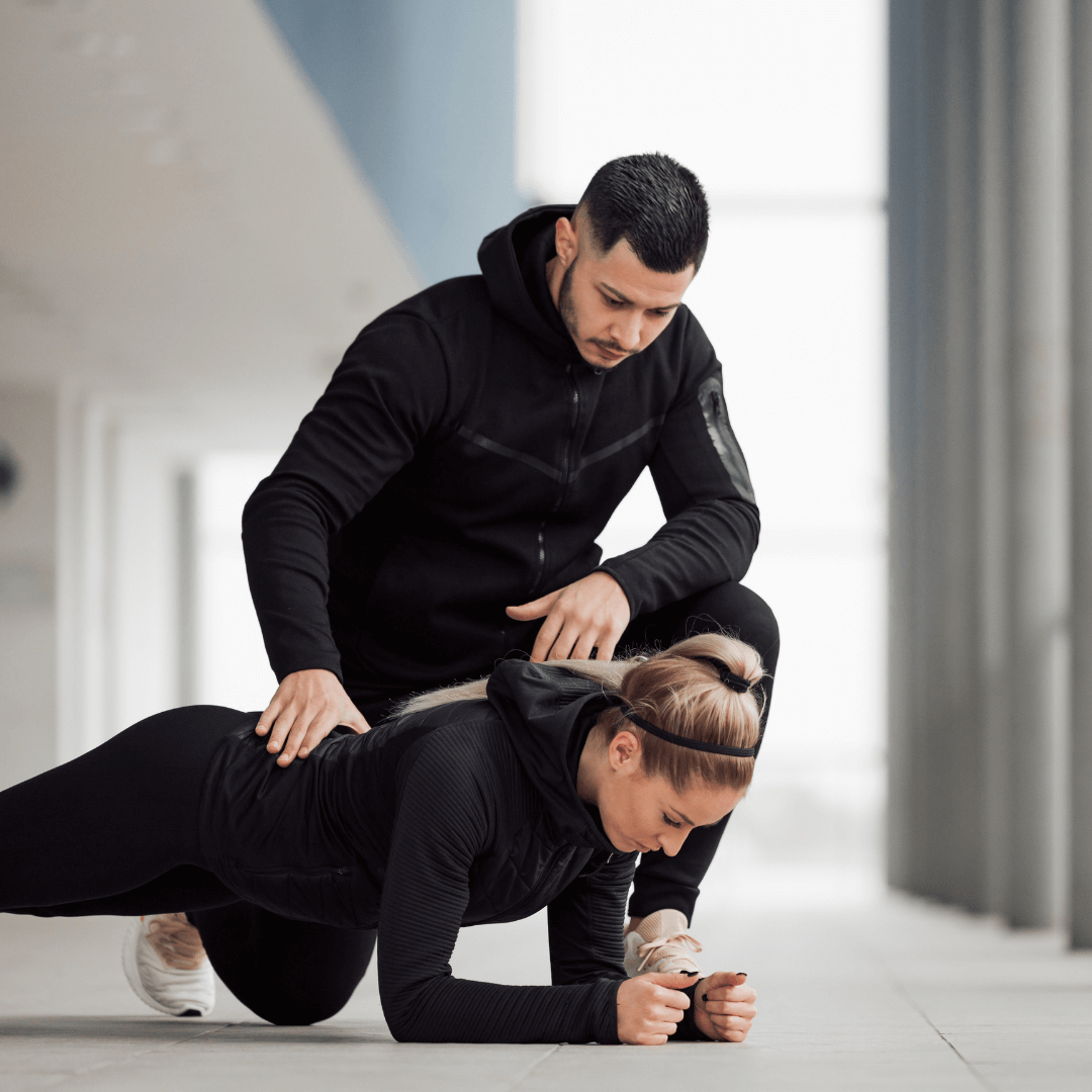 A certified personal trainer guides a client through a challenging workout in a home setting, highlighting the in-home personal training services.