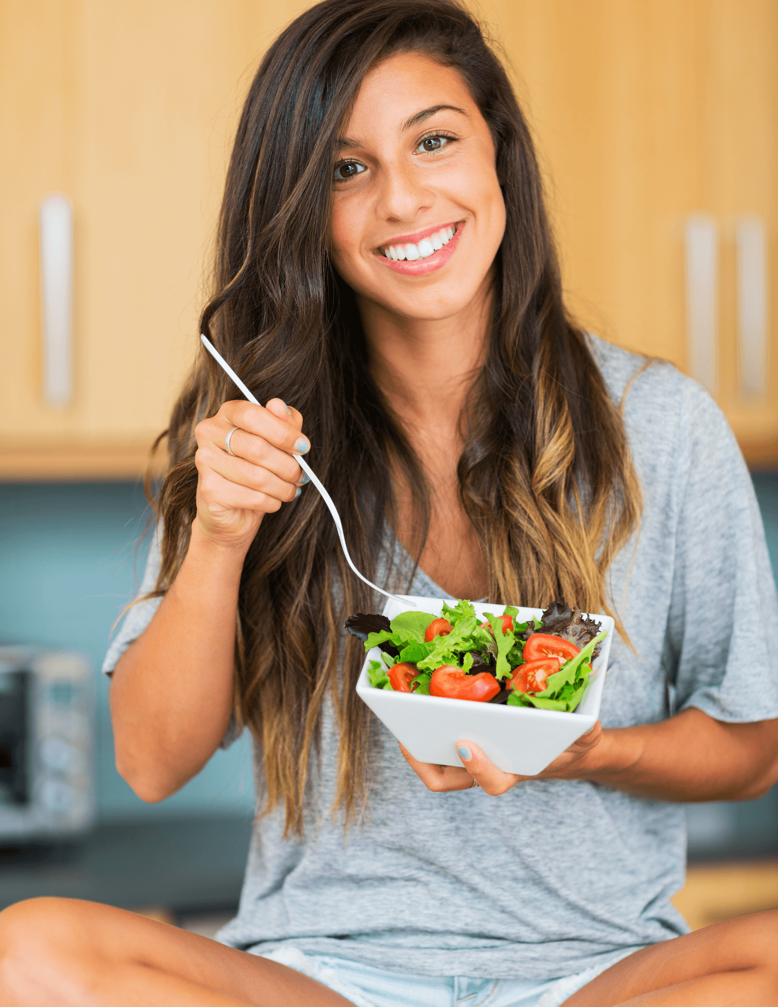 A woman smiles happily as she enjoys a healthy salad, demonstrating the personalized nutrition guidance offered by XLEVEL.